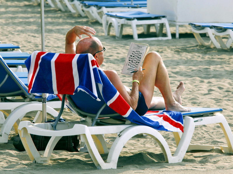 Turista a primera hora de la mañana intentando resolver un sudoku, Playa de Las Vistas, Los Cristianos, Tenerife, Islas Canarias, España