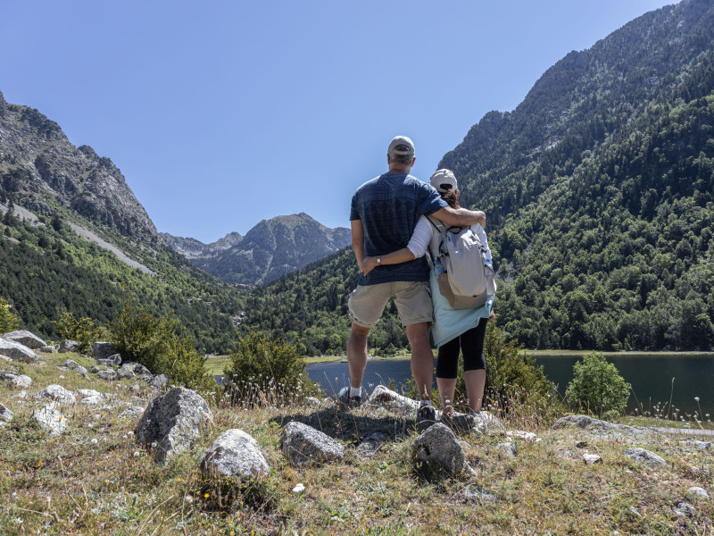 Una pareja de turistas de mediana edad se abrazan cerca de un lago de montaña en los Pirineos españoles