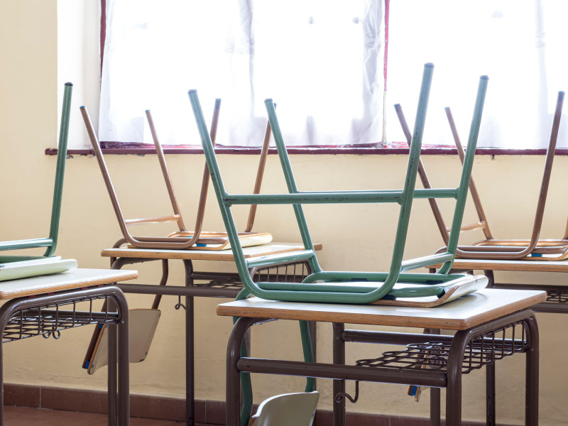 Fotografía de algunas sillas sobre mesas en un aula de una escuela primaria.