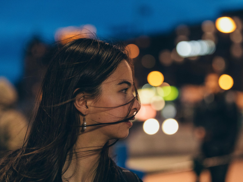 Vista de perfil de una mujer con el cabello al viento caminando por la calle