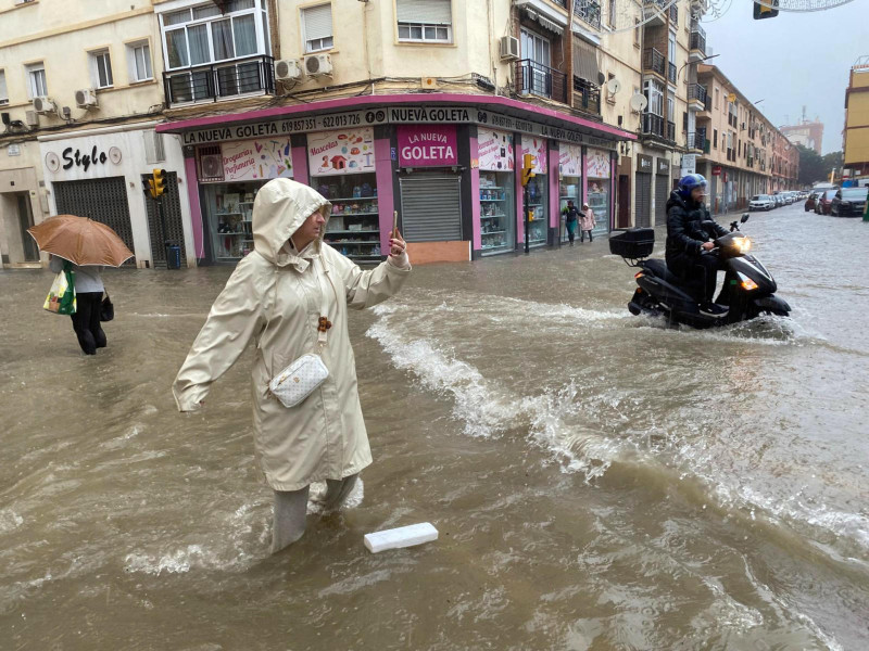 Una mujer hace fotos con el agua hasta las rodillas en Málaga donde las fuertes trombas de agua y granizo que se registraron este miércoles