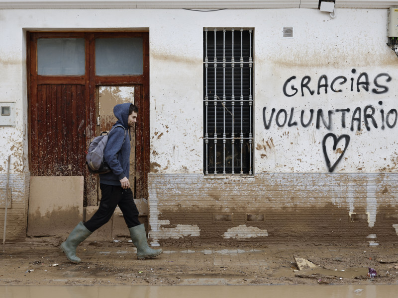 Un hombre camina junto a un graffitti que agradece la ayuda a los voluntarios mientras continúan las labores de limpieza en Paiporta, Valencia