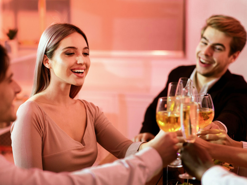 Compañeros de trabajo chocando copas durante la cena corporativa de celebración navideña en un restaurante