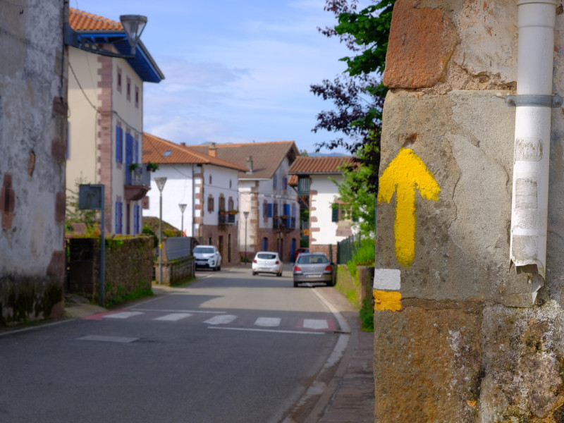 Flecha amarilla pintada en una casa en España que indica el camino a seguir para los caminantes hacia Santiago de Compostela y el Camino de Santiago