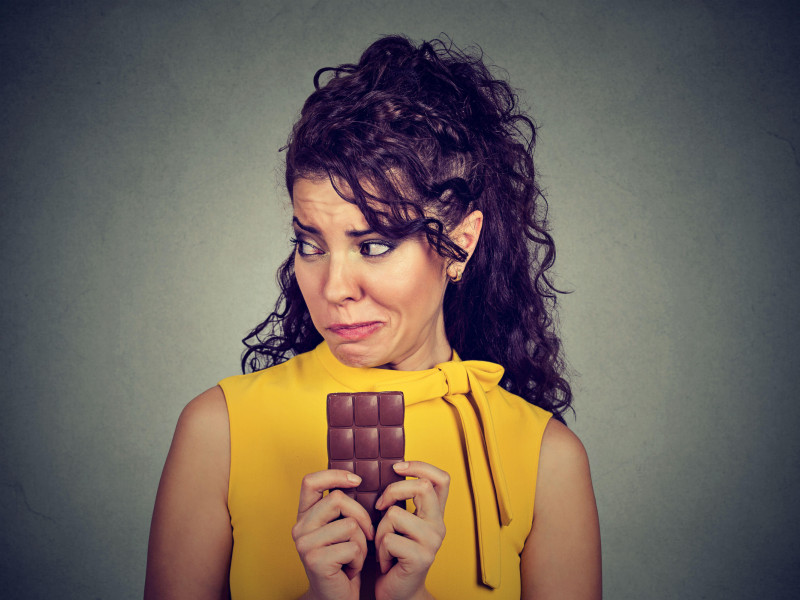 Retrato de una mujer deseando un chocolate dulce y sintiendo remordimiento