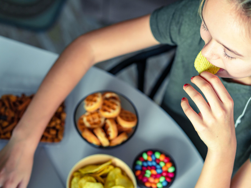 Una chica trabaja en una computadora y come comida rápida