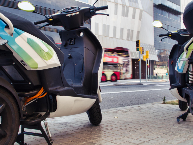 El tráfico pasa por delante de las bicis eléctricas aparcadas de un servicio de sharing en Barcelona, ​​para facilitar las necesidades de transporte y reducir la contaminación