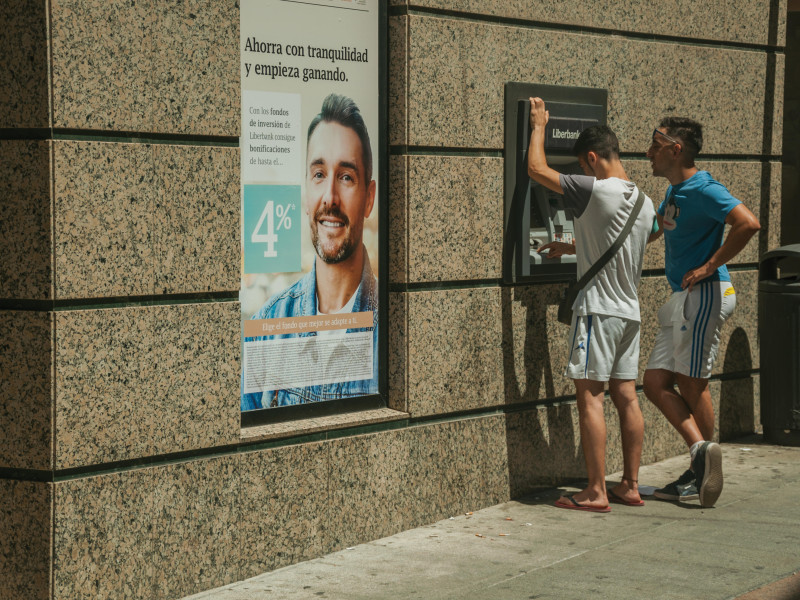 Jóvenes usando un cajero automático en la calle en un día soleado en Mérida