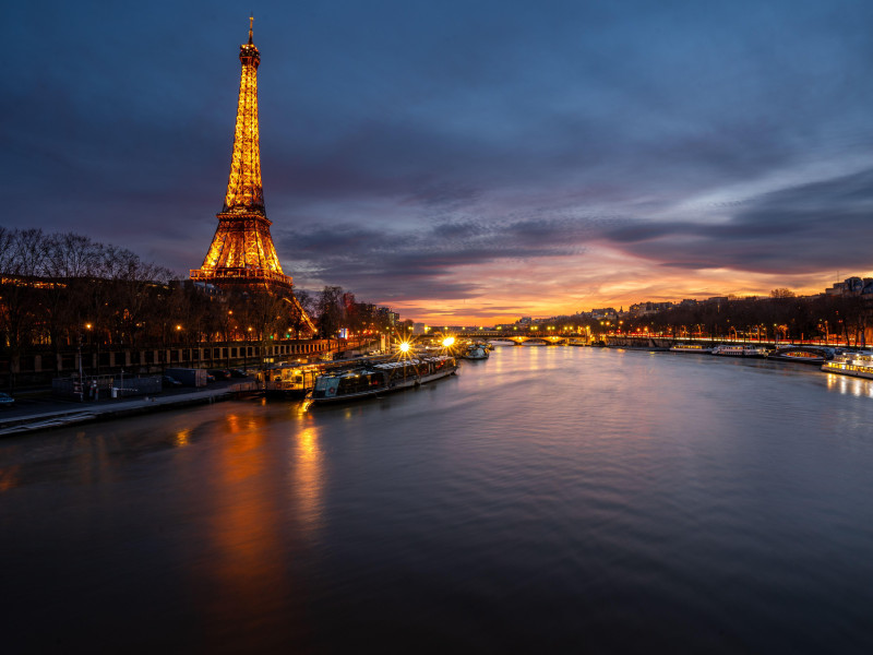 Torre Eiffel al atardecer, con el paisaje urbano parisino de fondo y el río Sena