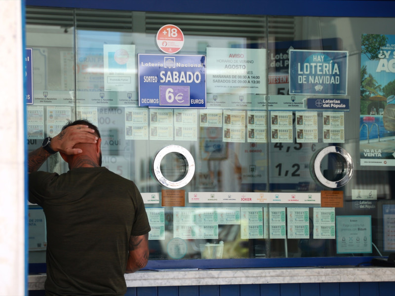 Una persona se dispone a adquierir un boleto en una Administración de Loterias, en el centro de Sevilla