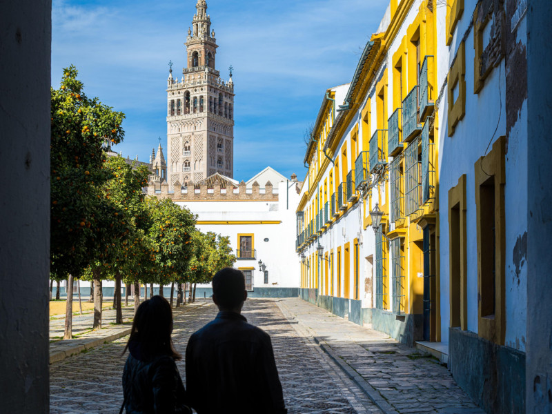 Pareja joven admirando la torre de la Giralda desde la plaza del Patio de Banderas, Sevilla, España