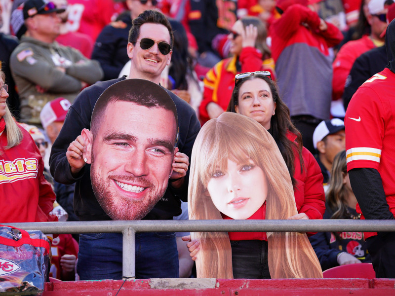 Fans de los Chiefs posan con caretas de la pareja de moda en la NFL.