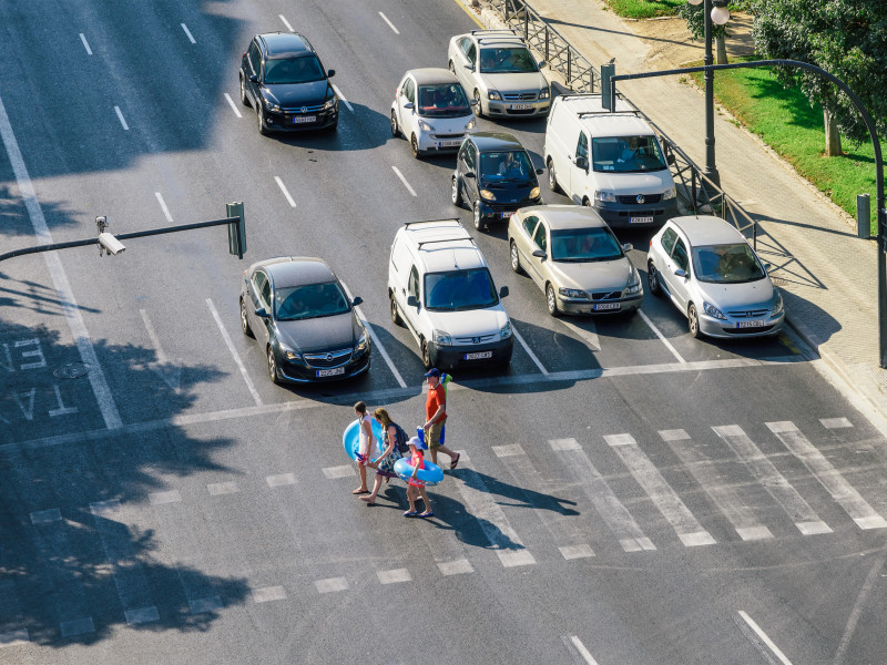 Coches esperando en el semáforo para que los peatones crucen la calle