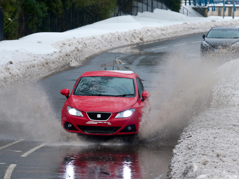 Un vehículo choca contra un gran charco causado por la nieve derretida