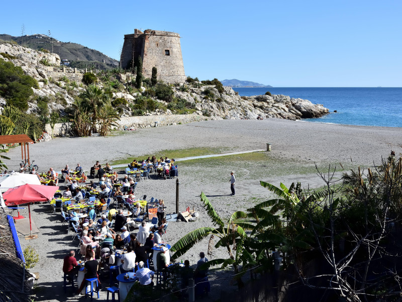 Chiringuito en la playa del Tesorillo de Almuñécar con la torre Velilla y el mar al fondo