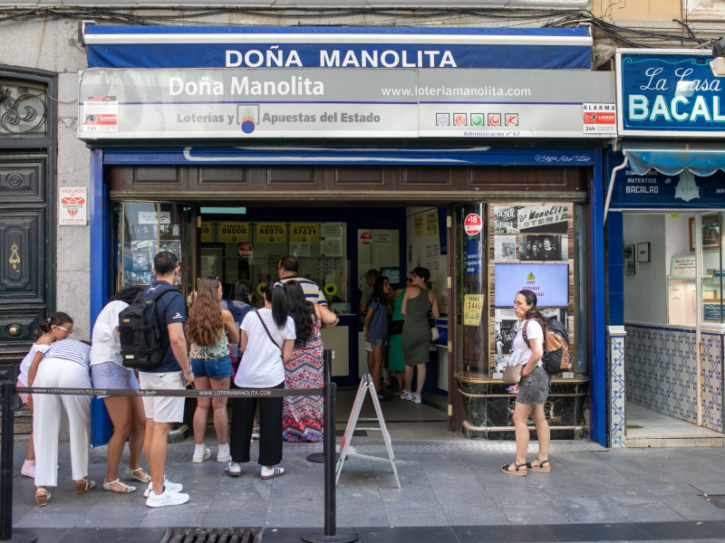 Un grupo de personas esperan en una cola para ser atendidos en la oficina de lotería de Dona Manolita para comprar un boleto de lotería de Navidad.