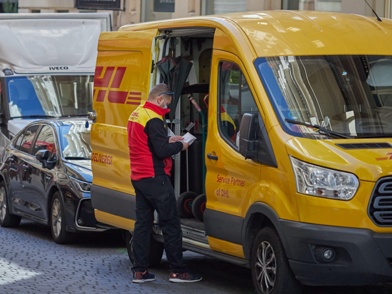 Trabajador de reparto de paquetes de DHL esperando delante del furgón de reparto (Madrid, España)