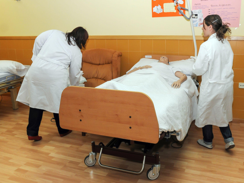 Estudiantes de enfermería cuidan a un paciente maniquí acostado en una cama de hospital en Zamora, España