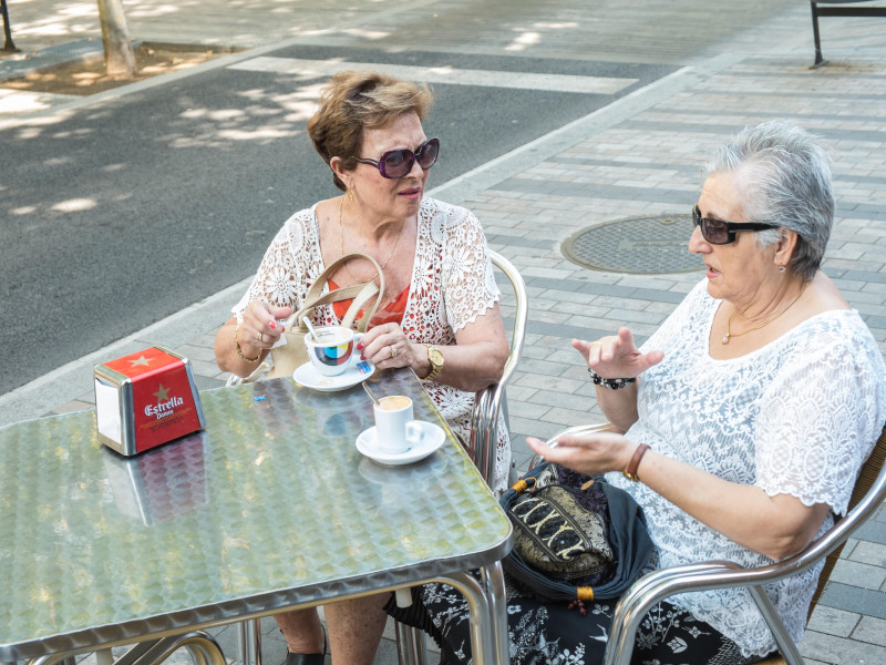 Una pareja de ancianos tomando un café en una mesa al aire libre en la calle, cafetería al aire libre, suburbio de la ciudad de Terrassa, Barcelona, ​​Cataluña