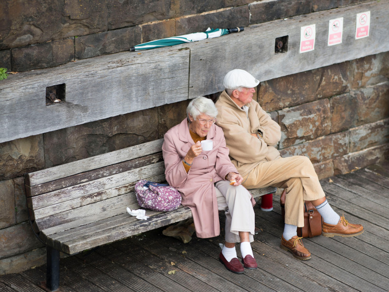 Una pareja de ancianos sentados en un banco disfrutando del tiempo libre.