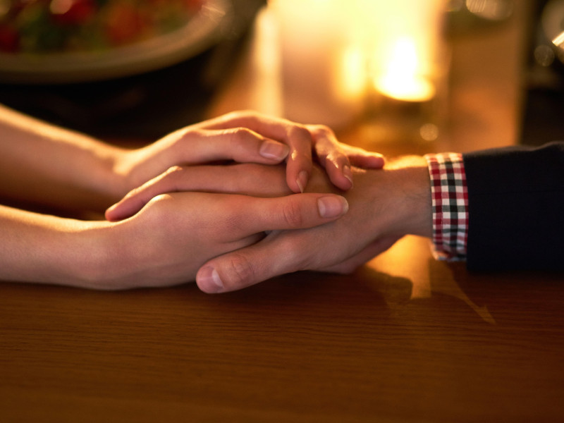 Fotografía recortada de una pareja joven tomada de la mano.