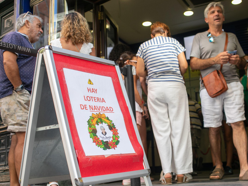 Un cartel indica la venta de loterías de Navidad a la entrada de la oficina de loterías de Doña Manolita en Madrid. Muchos turistas aprovechan las vacaciones de verano para comprar loterías de Navidad en la tradicional administración de loterías madrileñas de Doña Manolita en la calle Carmen en el centro de Madrid