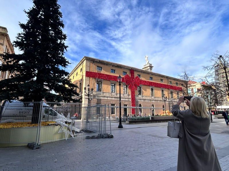 Una mujer fotografía el gran lazo rojo que decora el Antiguo Instituto Jovellanos de Gijón, en la Navidad de 2024