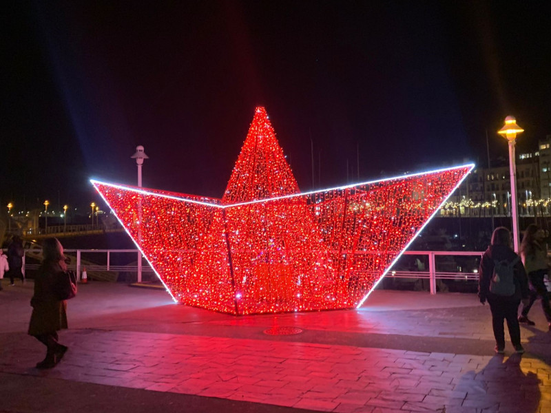 Barco de papel iluminado junto a 'Las Letronas' del Puerto Deportivo de Gijón, durante la Navidad de 2024