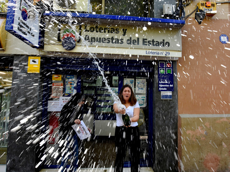 Una mujer salpica vino durante las celebraciones. Celebraciones de la lotería de Navidad 2018 de un cuarto premio del sorteo, Se ha vendido el número de Lotería 67774 en la Administración número 29 del Barrio de Santa Eulalia Dotado con 200.000 euros en cada serie