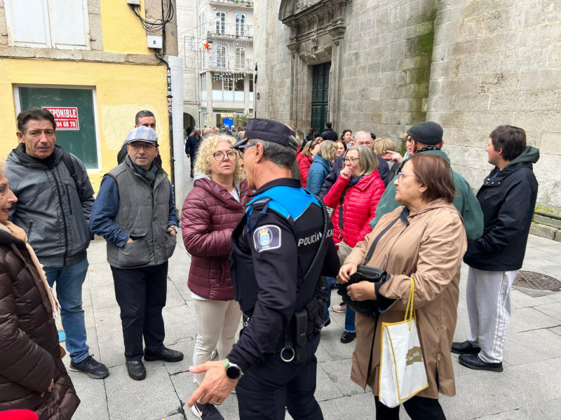 Un policía local trata de calmar los ánimos de la gente que hacía cola para retirar las entradas