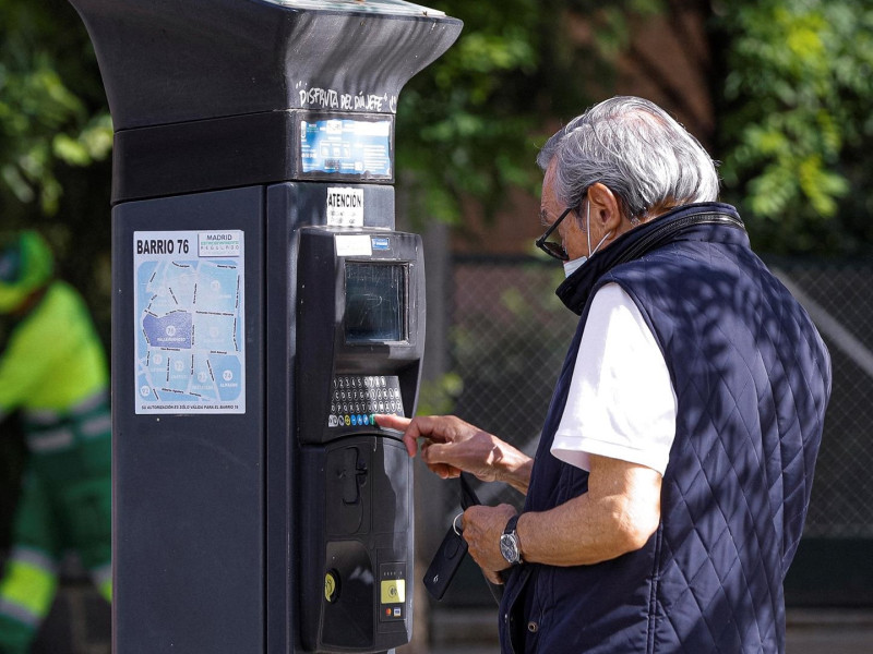 Un hombre saca su ticket en un parquímetro