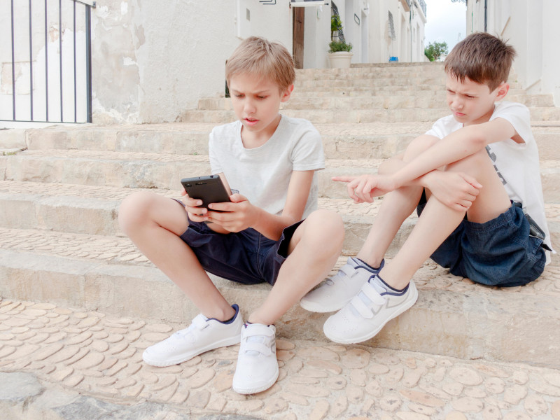 Niños hablando y usando el teléfono móvil al aire libre