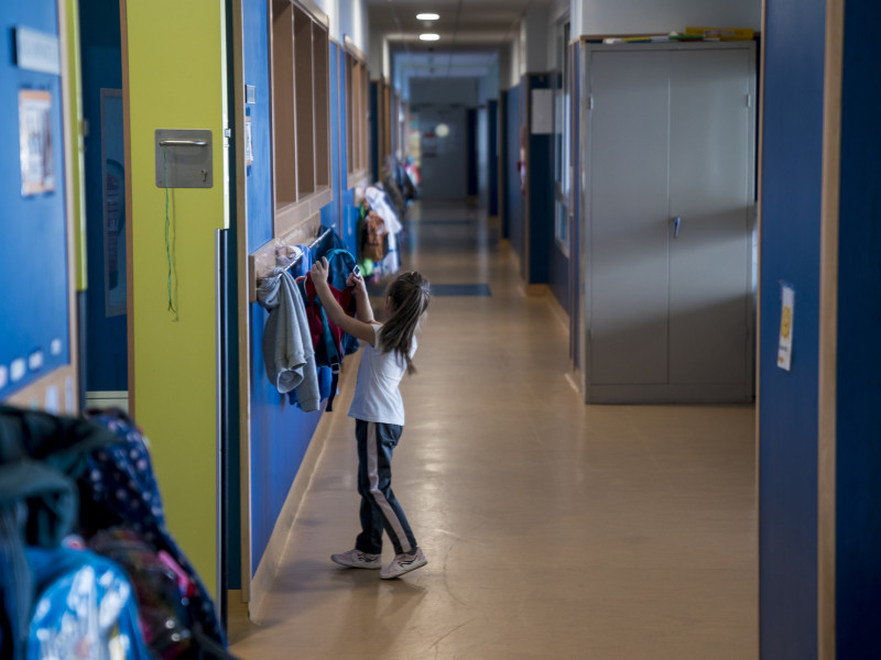 Una niña cuelga su mochila en un perchero durante las clases de un colegio público