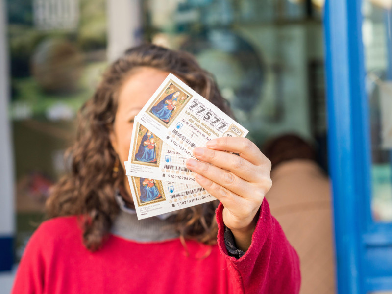 Una mujer a la entrada de una administración de lotería muestra algunos billetes de lotería para la tradicional Navidad.