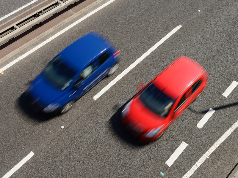 Vista aérea de un automóvil rojo y un automóvil azul circulando a toda velocidad por una carretera