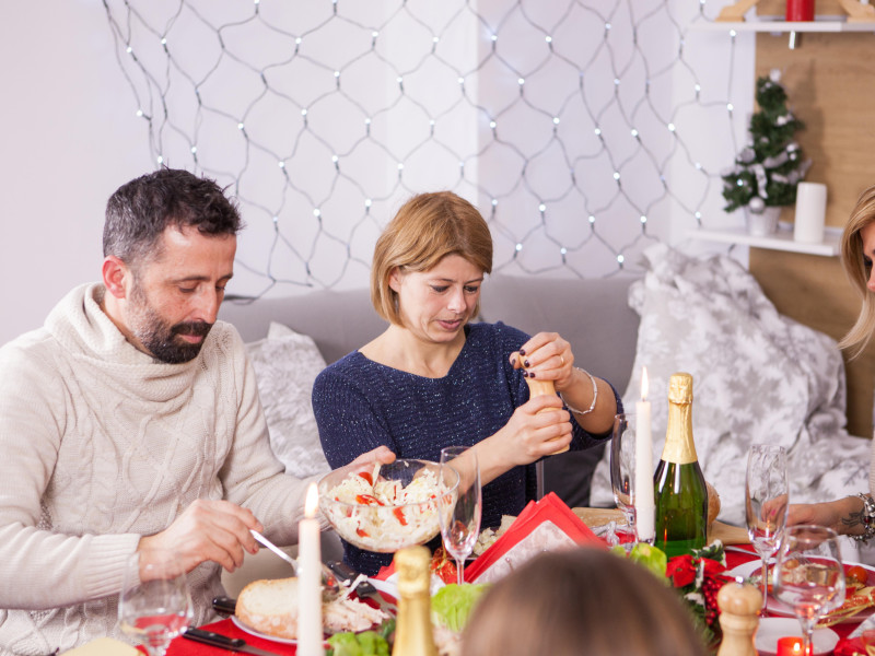 Mujer echando sal sobre la comida en la fiesta de Navidad