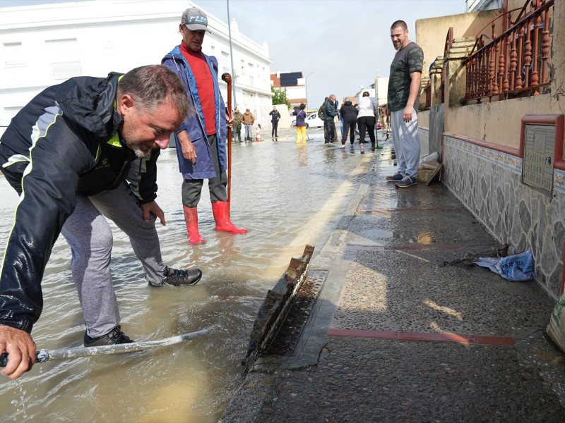 Varios vecinos de la calle Buen Pastor, de San Fernando, intentan desatascar una alcantarilla ,a 31 de octubre de 2024, en Cádiz