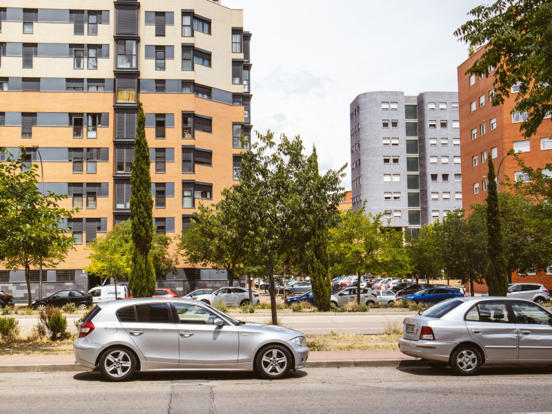 Calle de la ciudad en un día soleado de verano. Coches aparcados al costado de la carretera. Edificios de varios pisos en un moderno y tranquilo barrio residencial.