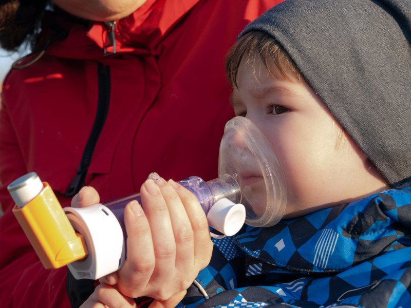 Un niño que sufre de asma con un inhalador