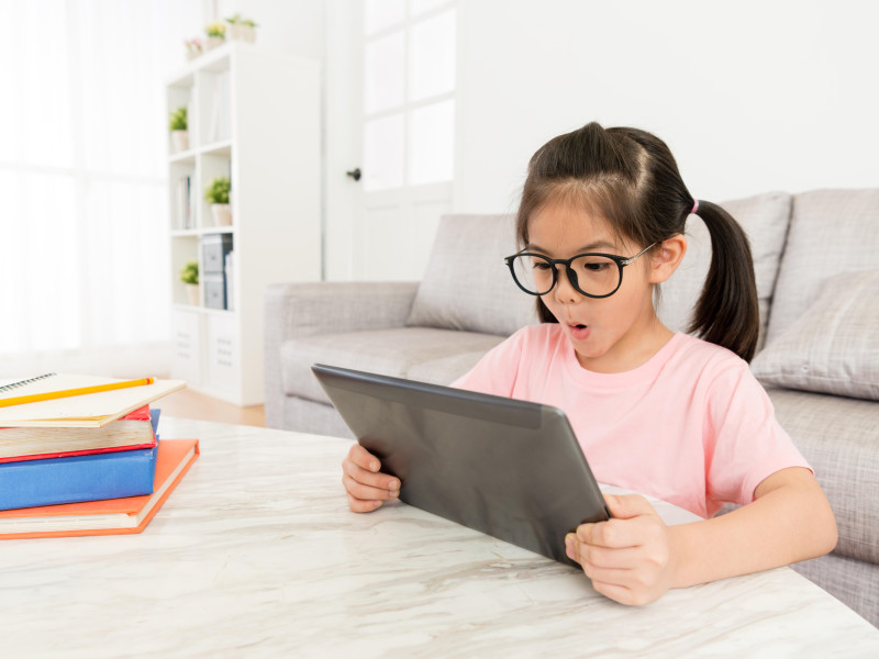 Hermosas niñas jóvenes que usan una computadora portátil para ver videos divertidos en línea se sienten alegres cuando terminan de estudiar los libros de texto de la escuela