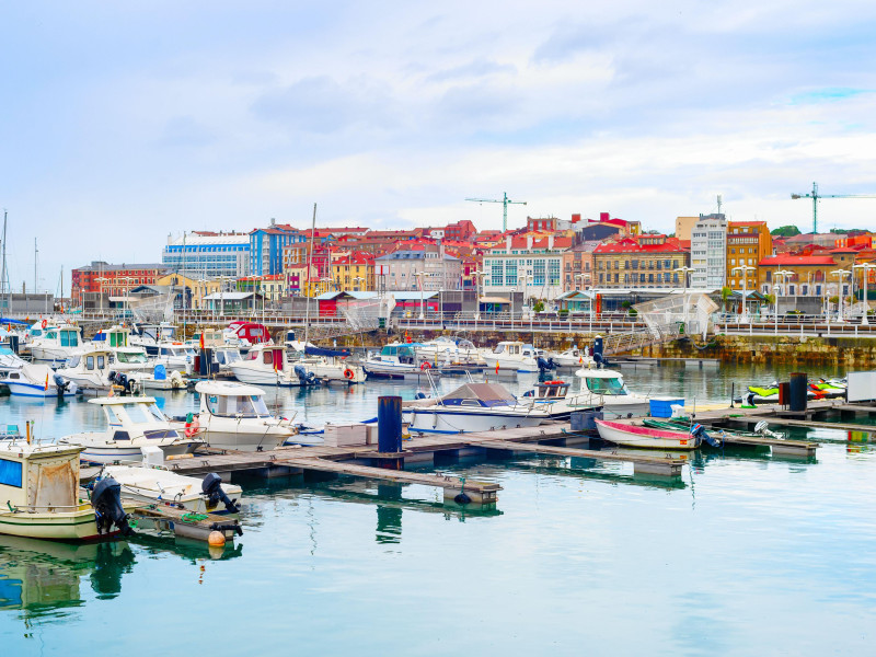 Vista de la ciudad nublada con yates y barcos a motor amarrados en los muelles del puerto deportivo, Gijón, Asturias, España