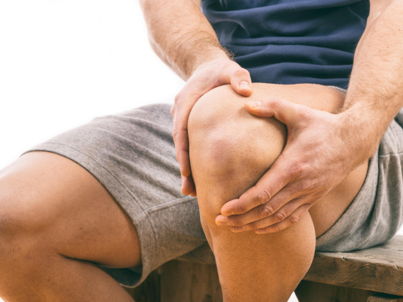 Hombre con dolor de rodilla sobre fondo blanco