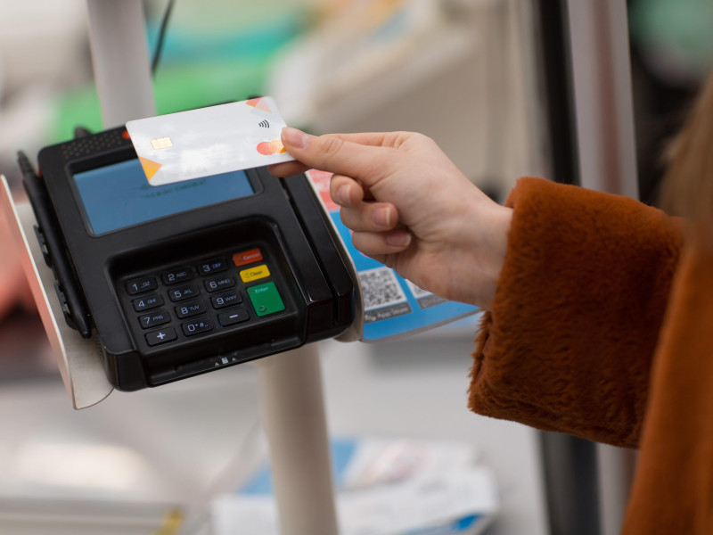 Mano de mujer con tarjeta de crédito bancaria paga compras en la caja de la tienda. Pago sin contacto en la nueva normalidad de las tiendas