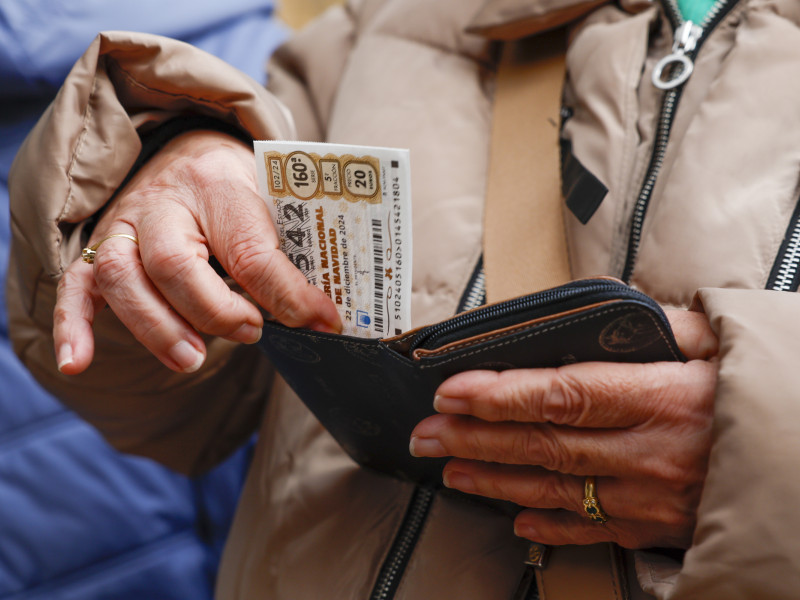 Una persona con un décimo de Lotería de Navidad en la mano