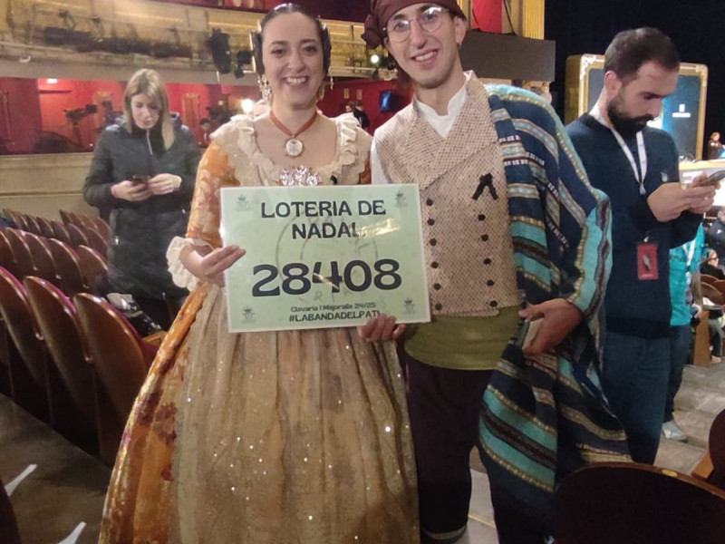 Asistentes al Sorteo de la Lotería de Navidad con su traje regional y la pancarta con el número que juegan