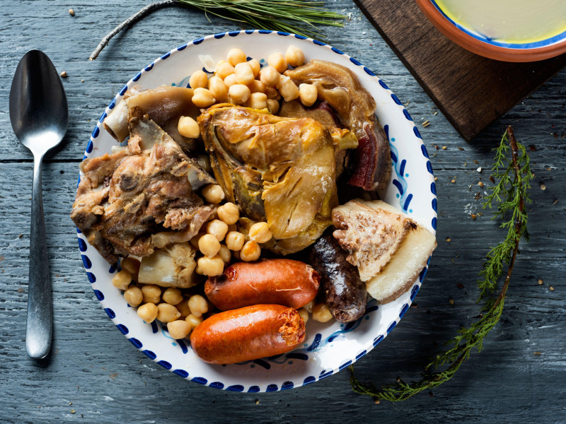 Cocido madrileño, típico de Madrid, España, con la sopa servida en un cuenco de barro y la carne y las verduras utilizadas en el caldo servidas en una bandeja.