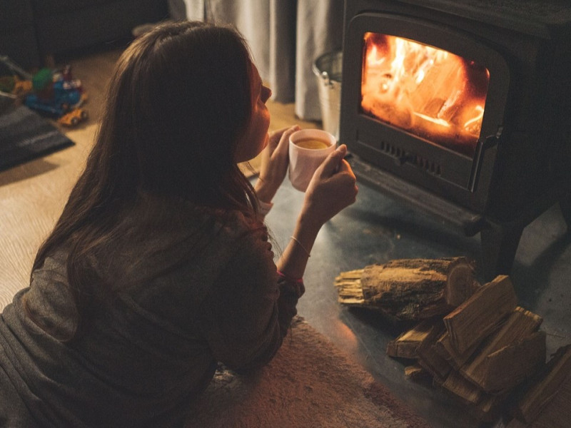 Una chica se toma café frente a una chimenea