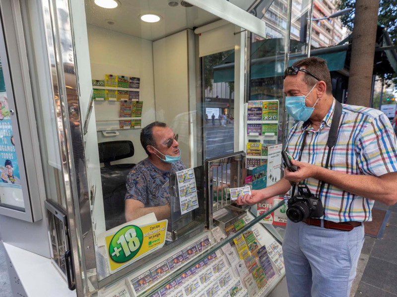 Un hombre compra un cupón en un puesto de la ONCE