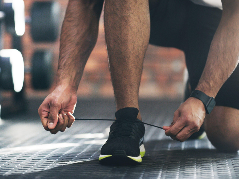 Preparándose para salir. Un deportista irreconocible atándose los cordones de los zapatos en un gimnasio.