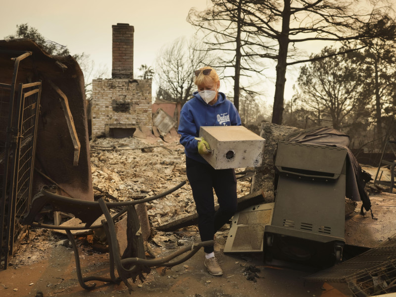 Melissa Young lleva algunas pertenencias que quedan de los restos de su casa que fue destruida por el incendio forestal de Eaton en Altadena, California, EE. UU., el 9 de enero de 2025.